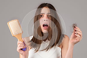 Hair loss. Woman is upset of hair loss. Portrait of sad girl with problem hair, isolated. Worried girl holding long