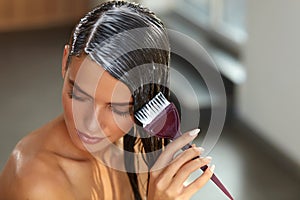 Hair Masks. Woman Applying Mask With Brush On Wet Long Hair