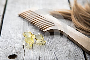 Hair nurishment. vitamin serum capsule on wooden background