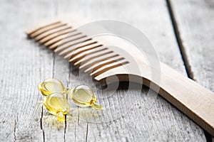 Hair nurishment. vitamin serum capsule on wooden background