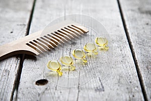 Hair nurishment. vitamin serum capsule on wooden background