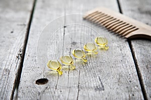 Hair nurishment. vitamin serum capsule on wooden background