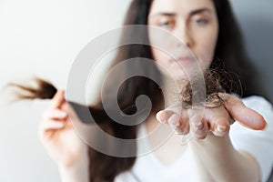 Hair problem. A blurry portrait of a sad woman showing a close-up of a fallen bunch of hair on the palm of her hand. The