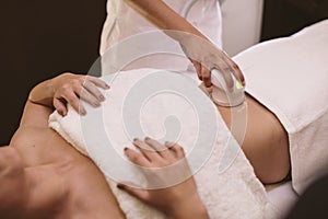 Hair removal cosmetology procedure from a therapist at cosmetic clinic.