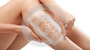 Hair removal with wax strips. Epilation of the legs at home. The girl removes unwanted hair on her legs in close-up