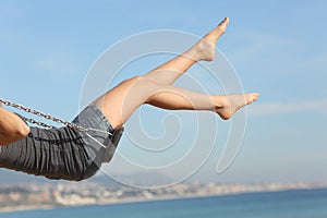 Hair removed woman legs swinging on the beach photo