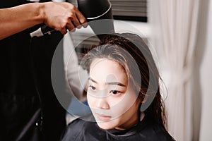 Hair salon concept a male hairdresser using a hair dryer drying a female customerâ€™s wet hair after hair wash process