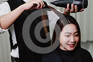 Hair salon concept a male hairdresser using a hair dryer drying a female customerâ€™s wet hair after hair wash process