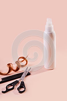 Hair spray bottle with curly lock of hair, scissors and a comb on beige background.