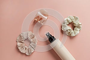 Hair spray and two scrunchies with hair pin on pink background-colorful hair tools and accessories