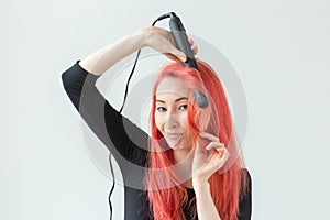 Hair style, hairdresser and people concept - stylish red-haired woman with curling iron on white background.