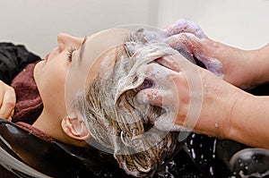 Hair stylist applying coloring purple shampoo after hair dyeing.