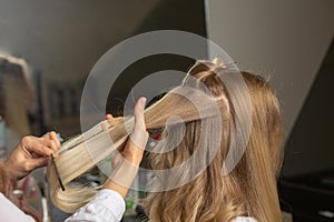 Hair stylist combing woman`s hair