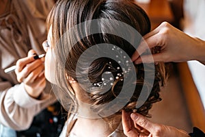 A hair stylist and make-up artist prepare a bride for the wedding day