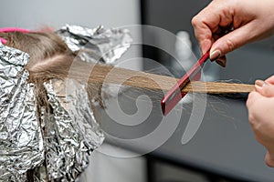 Hair stylist makes bouffant using comb on thin strands. Shatush technique for hair bleaching