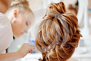 Hair stylist makes the bride before the wedding