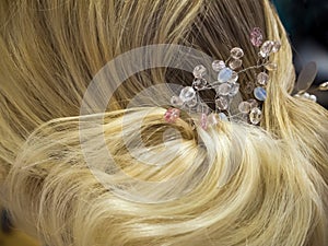 Hair stylist makes the bride a wedding hairstyle with hair detail accessory, closeup rear view.