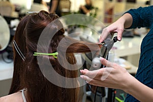Hair stylist making ringlets to brunette woman. Hairdresser work