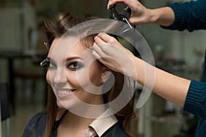 Hair stylist making ringlets to brunette woman. Hairdresser work