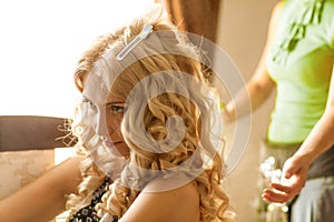 Hair Stylist preparing beautiful bride before the wedding in a morning