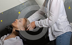 Hair stylist washing client`s hair before hair coloring