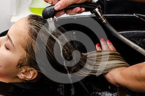 Hair stylist washing hair of a young pretty woman