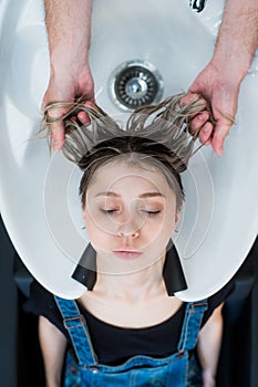 Hair-stylist washing teen girl hair with shampoo