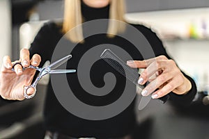Hair stylist woman hands hold scissors and comb close-up. Hairdressing and hair care