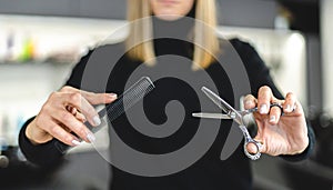 Hair stylist woman hands hold scissors and comb close up. Hairdressing and hair care