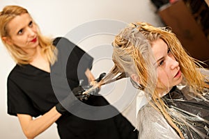 Hair stylist at work - hairdresser applying a color on custom