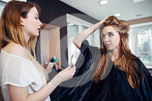 Hair stylist working on female customer s hairdo clipping strands with hair pins in hairdressing studio