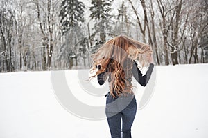 Hair to the different sides. Rear view of girl with long hair runs near the forest to the automobile in wintertime