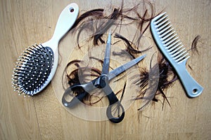 Hair tools, beauty and hairdressing concept. Scissors, brushes and comb with cut hair on brown background