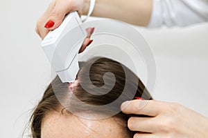 Hair treatment. A trichologist examines the hair roots with a special digital microscope