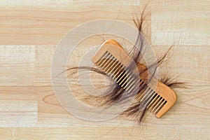 Hair on wooden comb on wooden floor with copyspace. Conceptual f