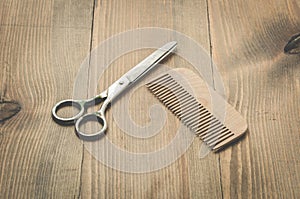 Hairbrushes, sprayer and a scissors on a wooden board, barbershop concept