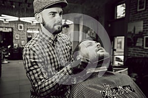 Haircut in the barbershop. Close up view of young bearded man, hairdresser combs the client's beard