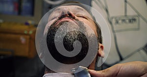 Haircut beard with in a barber shop. A professional hairdresser paints a client man beard with black hair dye. Handsome