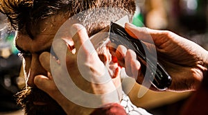 Haircut concept. Man visiting hairstylist in barbershop. Barber works with hair clipper. Hipster client getting haircut