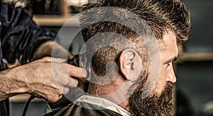 Haircut concept. Man visiting hairstylist in barbershop. Barber works with hair clipper. Hipster client getting haircut
