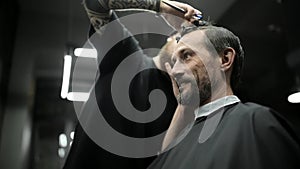 Haircut of dark haired bearded man in barbershop