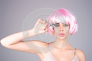 Haircut. Portrait of young woman hairdresser cutting hair with scissors. Girl with beautiful hair look at scissors