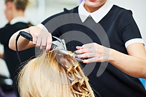 Hairdo in beauty salon. hairdresser making coiffure with curl to wonam