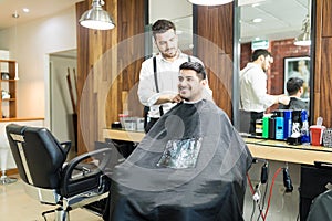 Hairdresser Adjusting Drape On Customer In Salon