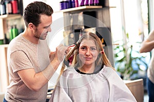 Hairdresser applying color client at salon, doing hair dye