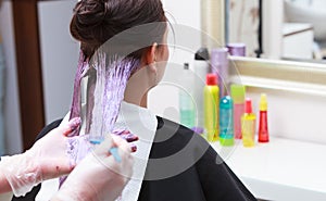 Hairdresser applying color female customer at salon, doing hair dye