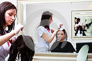 Hairdresser applying color female customer at salon, doing hair dye