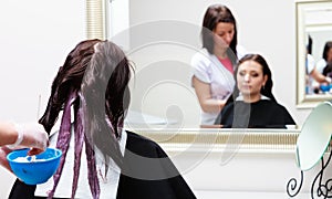 Hairdresser applying color female customer at salon, doing hair dye