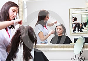 Hairdresser applying color female customer at salon, doing hair dye