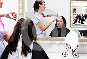 Hairdresser applying color female customer at salon, doing hair dye